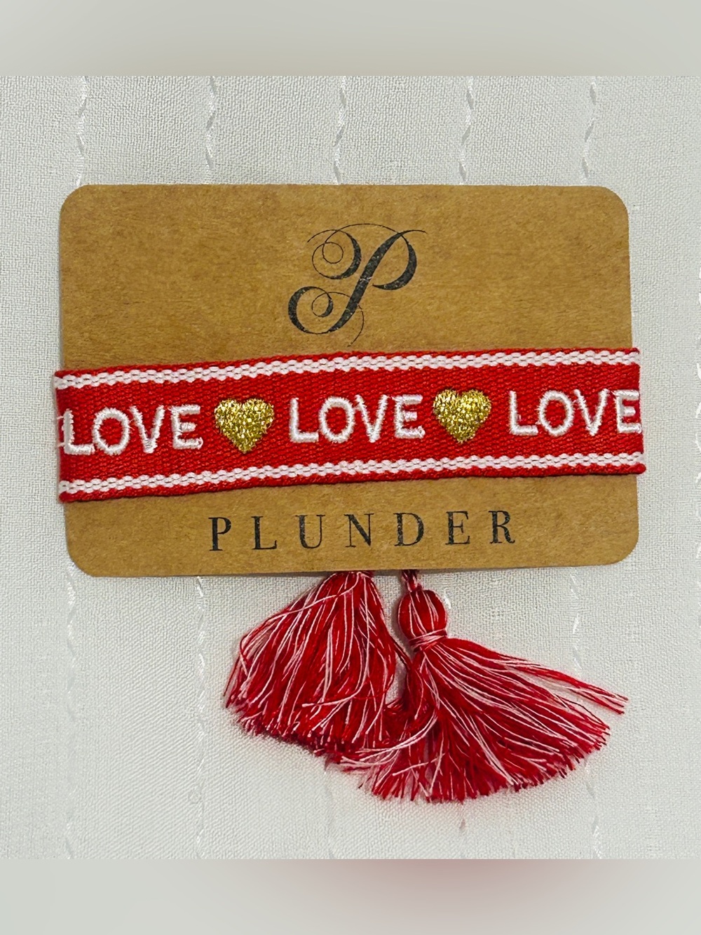 Plunder Design red and white woven bracelet featuring word LOVE and gold hearts.